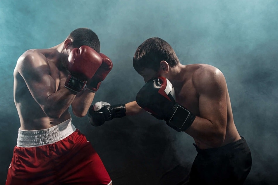 Dos boxeadores profesionales intercambiando golpes durante un combate intenso en el ring, rodeados de humo para un efecto dramático.