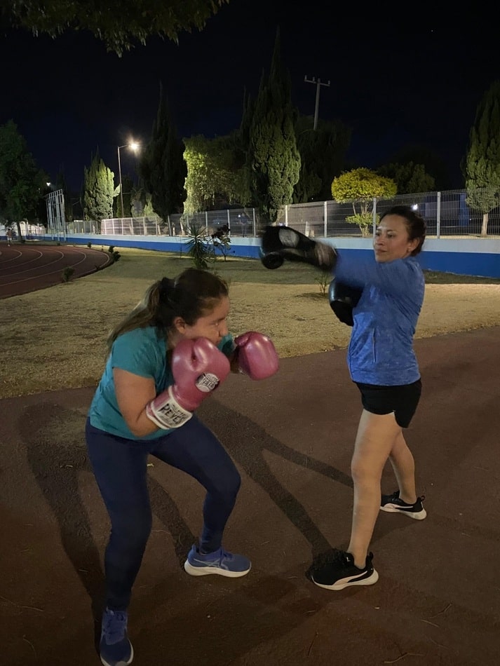 Alumnas practicando clases de box en Cholula durante entrenamiento nocturno al aire libre.