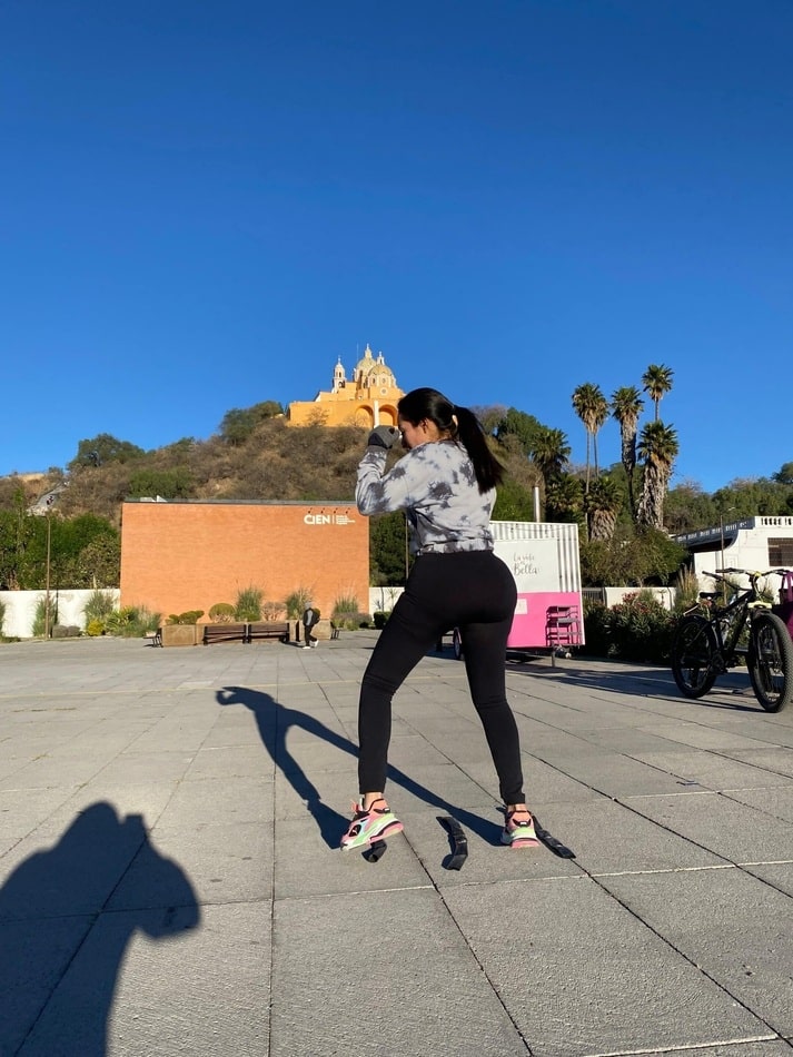 Alumna entrenando box en Cholula con vista a la iglesia de los Remedios, combinando deporte y paisaje local.